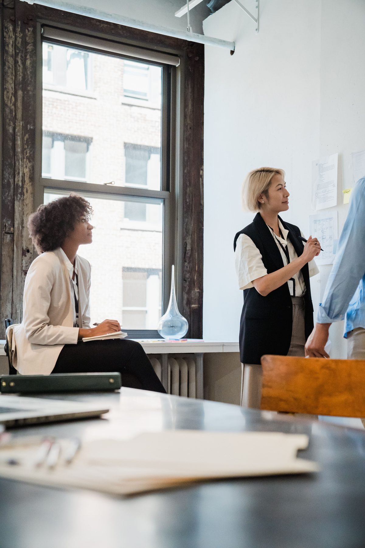 Two colleagues planning at a whiteboard in a bright office