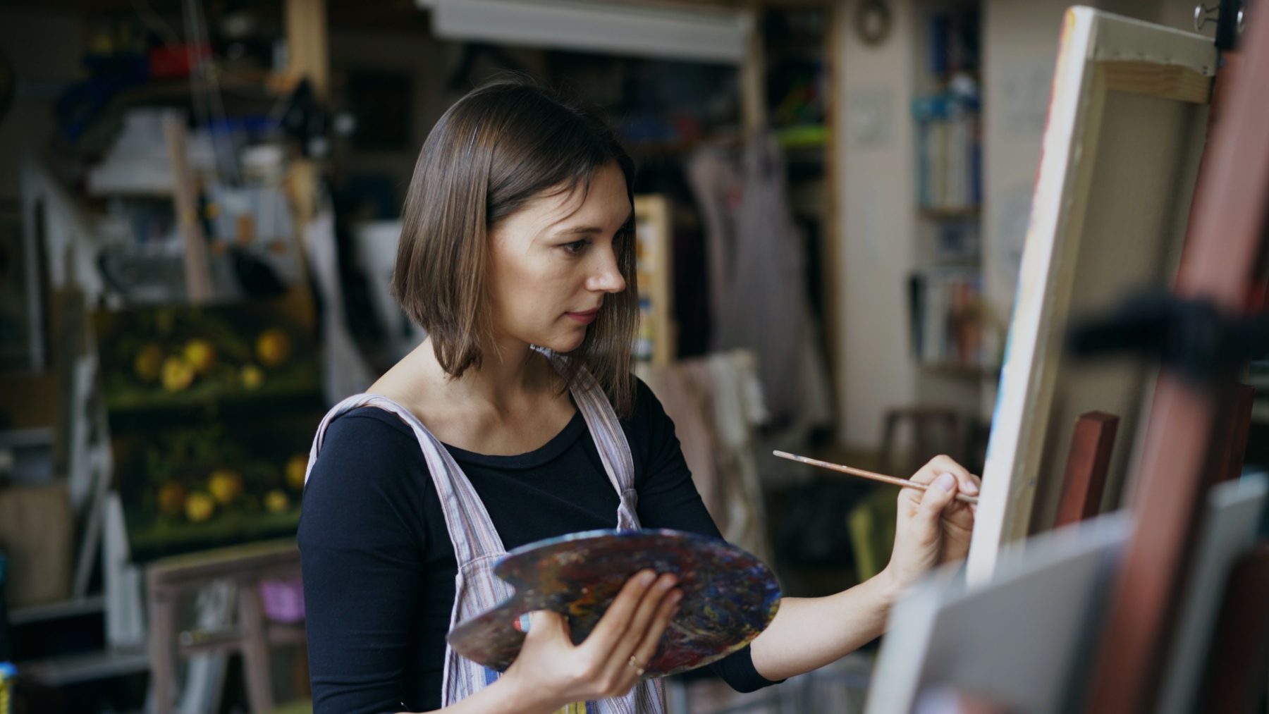 A florist in an apron working at her bench in a busy studio