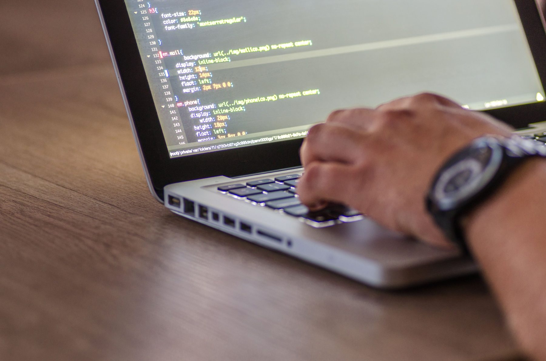 An engineer typing on a laptop at a wooden desk
