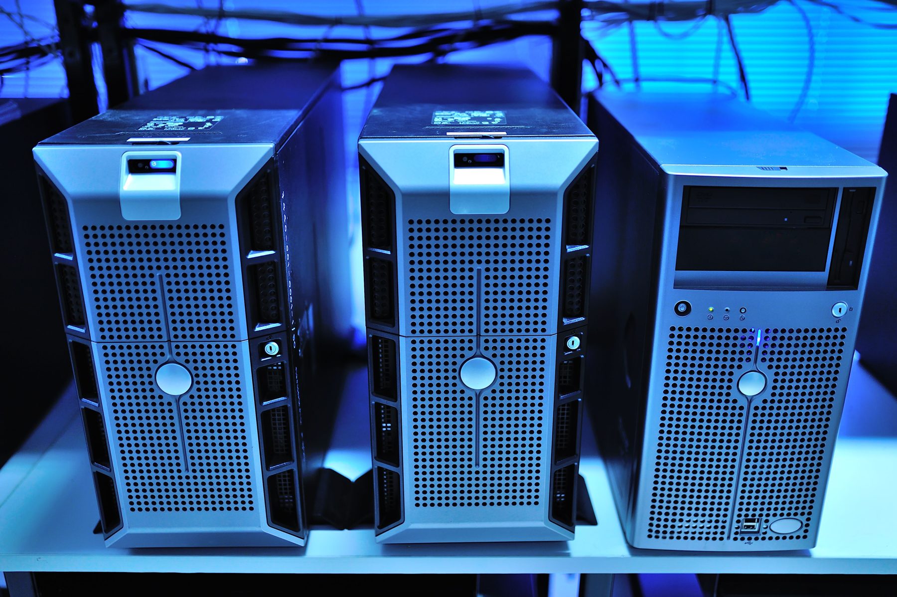 Three servers sitting on a shelf under blue light