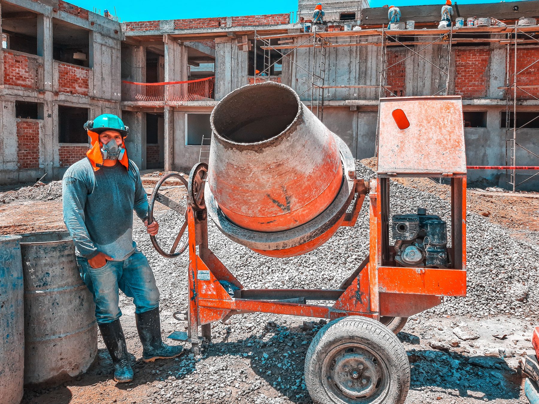 A builder beside a concrete mixer on a groundworks site