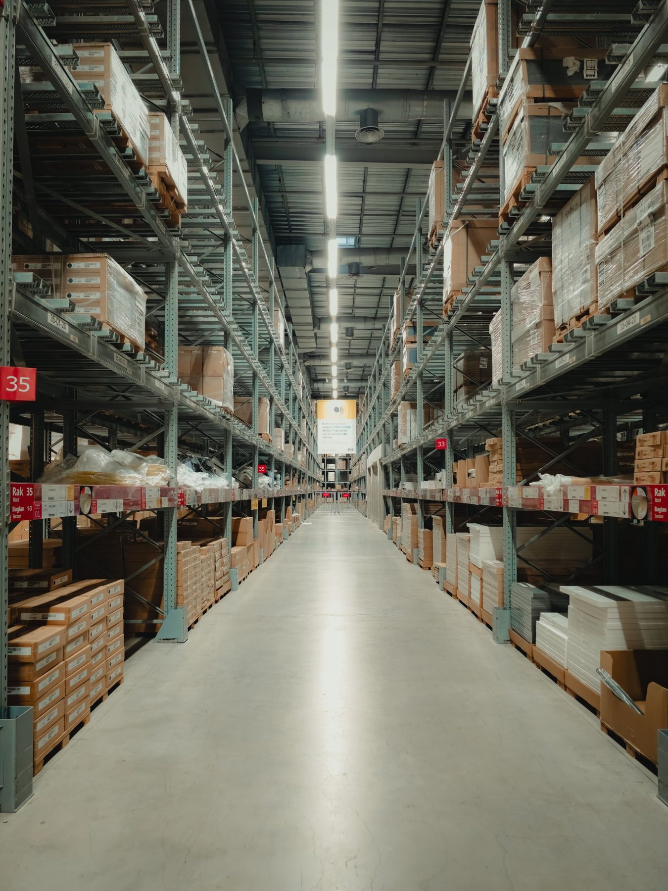 A tall warehouse aisle lined with racking in cool light