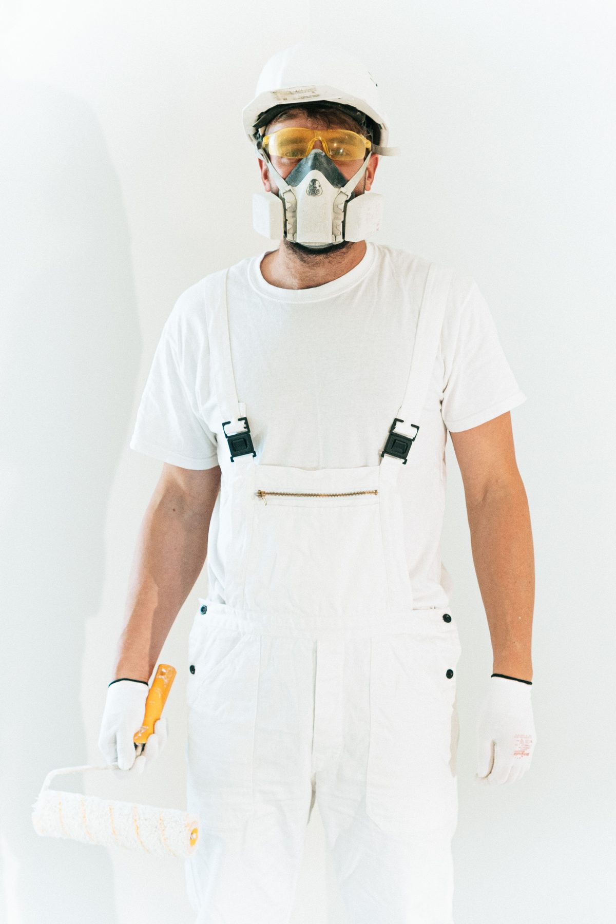 A pest control technician in a white suit, goggles and respirator